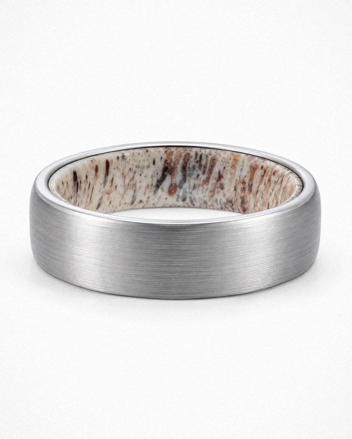 Brushed silver tungsten wedding ring with antler inner sleeve shown lying flat