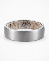 Brushed silver tungsten wedding ring with antler inner sleeve shown lying flat