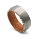 Angled view of a silver tungsten whiskey barrel wedding ring with a real oak wood interior.