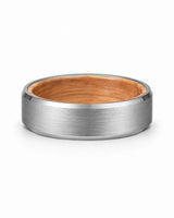 Silver brushed tungsten wedding ring with polished beveled edges and a whiskey barrel wood interior photographed from a low front angle on a white background.