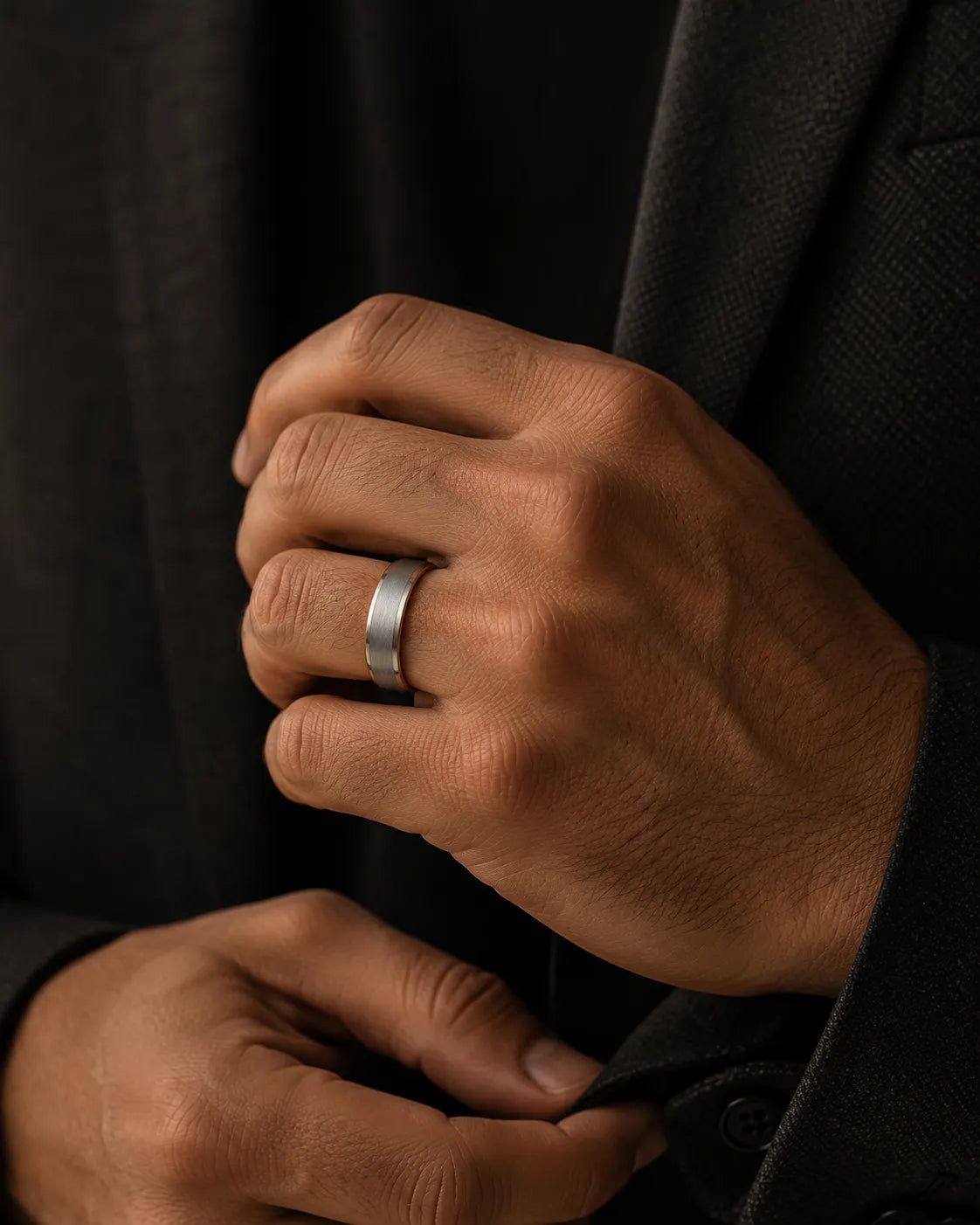 Man wearing a silver brushed tungsten wedding ring with polished beveled edges and a whiskey barrel wood interior while adjusting a charcoal jacket.