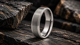 Brushed silver titanium wedding ring on dark textured stone