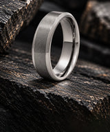 Brushed silver titanium wedding ring on dark textured stone