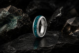 Silver tungsten wedding ring with turquoise gemstone inlay on dark volcanic stone background
