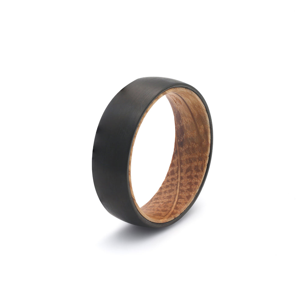 Black whiskey barrel wedding ring with reclaimed oak wood sleeve