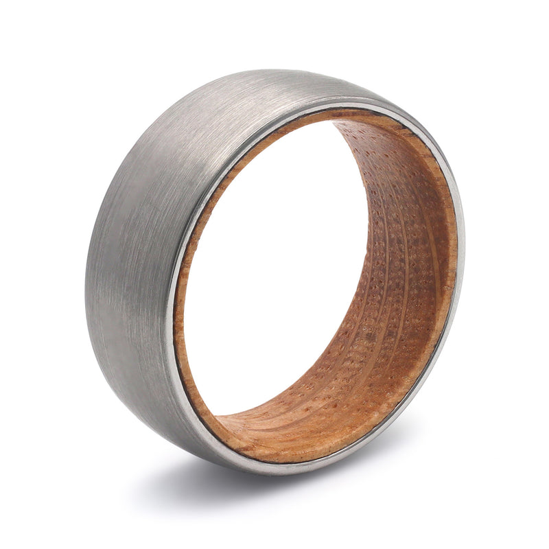 Silver tungsten whiskey barrel wood wedding ring on a soft light background with rugged masculine styling.