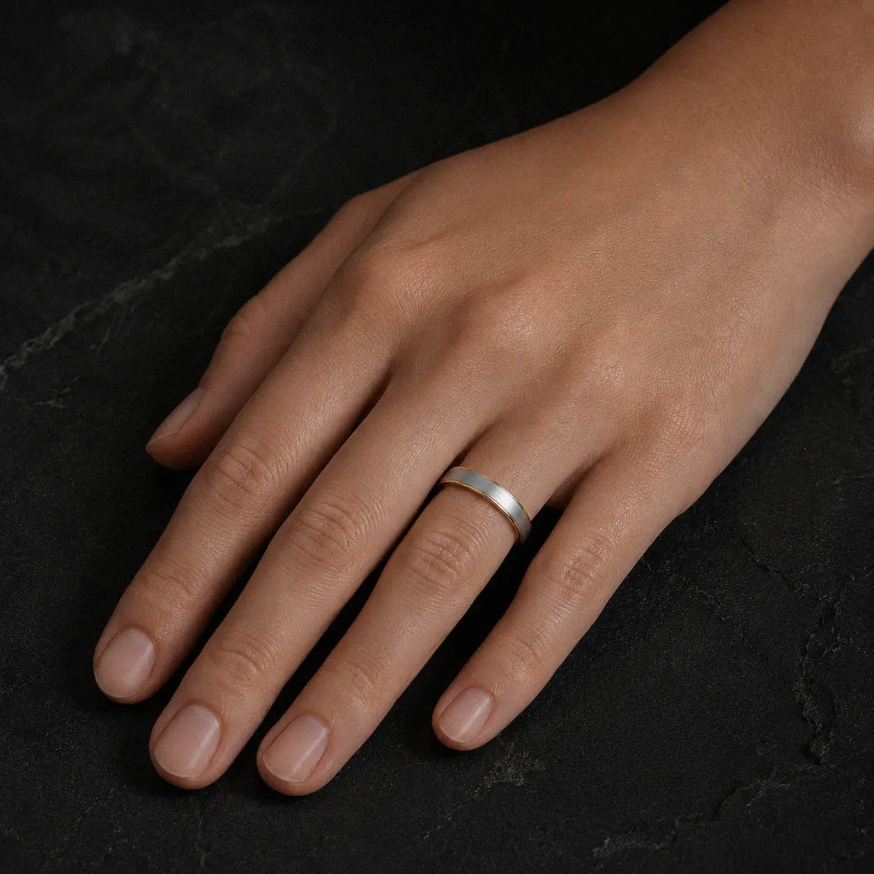 Woman wearing an 4mm brushed silver tungsten wedding ring with polished gold inner band