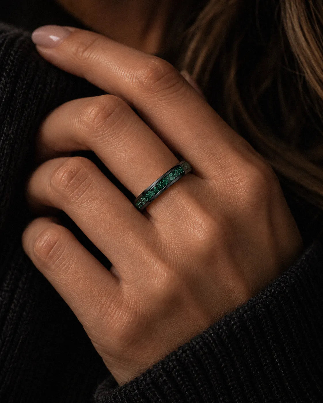 Woman wearing a 4mm black wedding ring with crushed emerald gemstone inlay