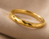 Ultra close-up macro photograph of a women’s faceted gold wedding ring showing polished reflective detail and craftsmanship