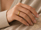 Woman wearing a faceted gold wedding ring with soft luxury feminine styling and neutral knitwear
