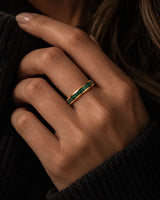 Woman wearing a 4mm gold wedding ring with crushed emerald gemstone inlay