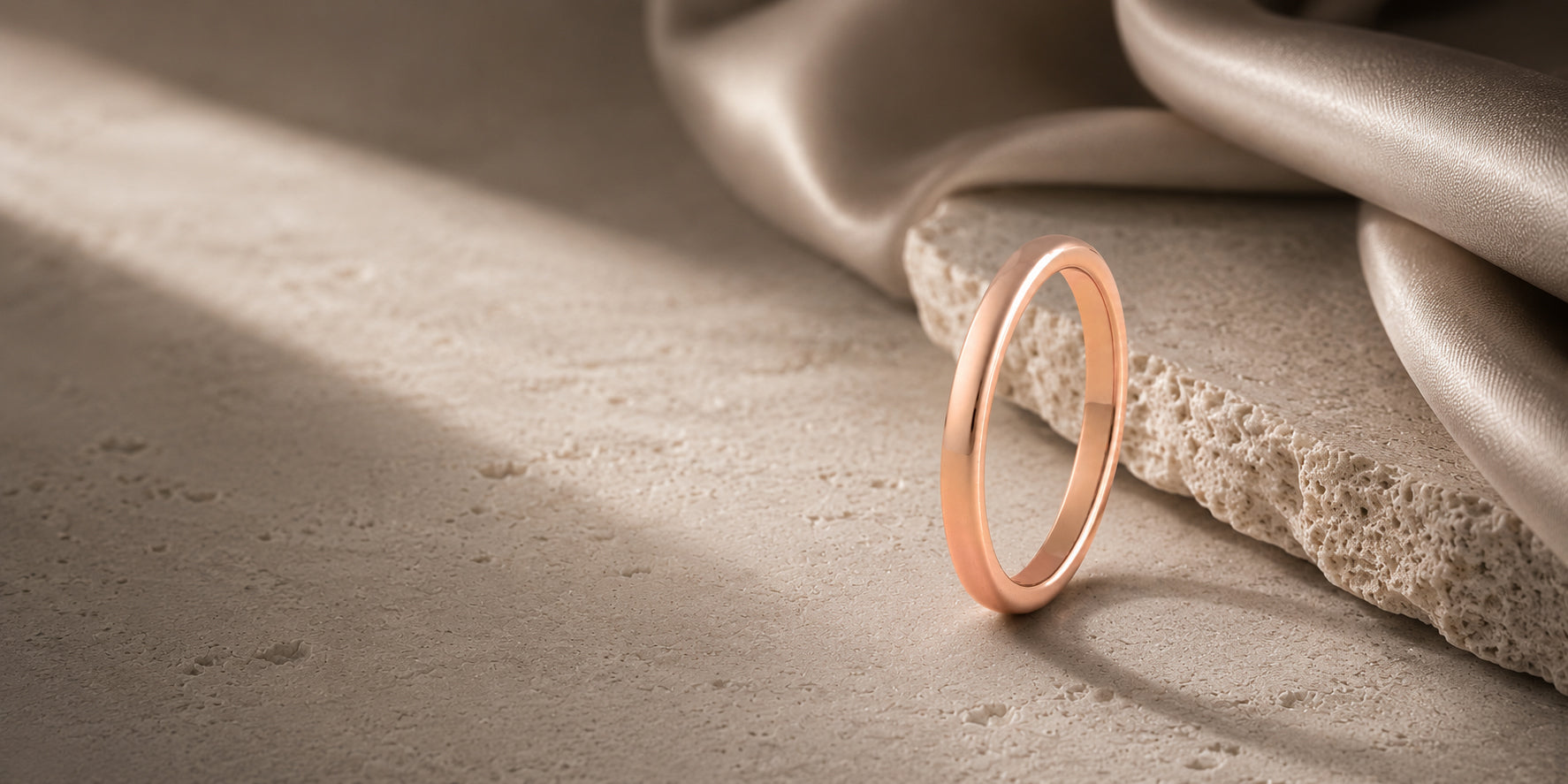 Rose gold women’s wedding ring hero banner with dark textured stone background and negative space for website text overlay.
