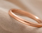 Ultra close-up macro photograph of a polished rose gold women’s wedding ring showing smooth reflective finish and fine metal detail.