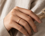 Woman wearing a slim rose gold wedding ring in a luxury lifestyle setting with soft cinematic lighting and premium neutral styling.
